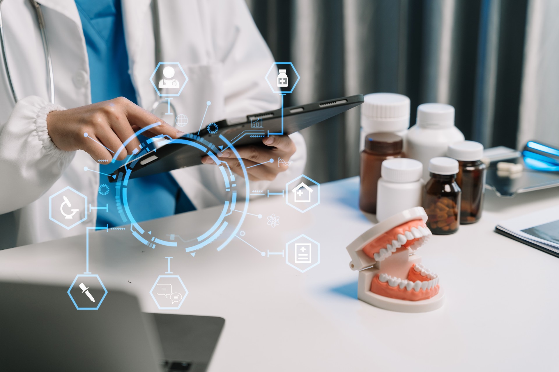 Doctor stomatologist is working on a Tablet computer and tooth model in a modern office in the morning at the desk.